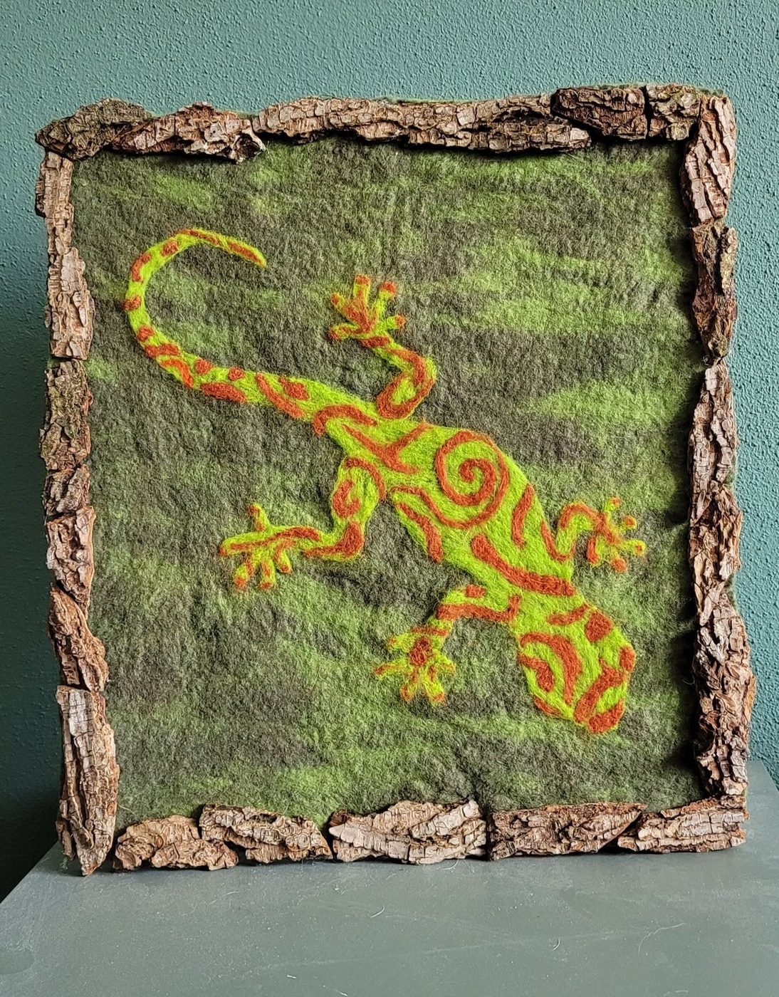 Naaldgevilte gekko op groen vilt met schorslijst